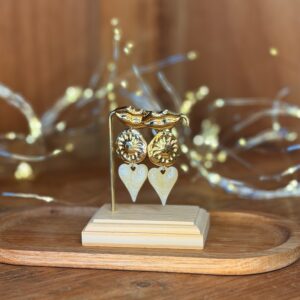 Boucles d’oreilles dorées sculptées avec pendentifs cœurs ivoire nacré, présentées sur plateau bois