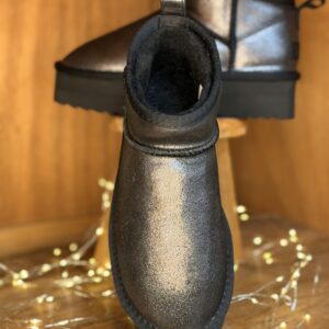 Boots femme irisée argent métallisé, tige courte fourrée, semelle plateforme noire crantée, présentées sur tabouret en bois avec guirlande lumineuse.
