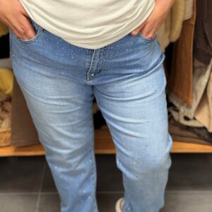 Pantalon en jean taille haute, bleu clair délavé effet used, porté par une femme ronde, coupe droite légèrement évasée aux chevilles, poches avant et arrière, détails strass discrets sur les jambes.