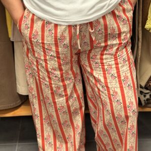 Pantalon fluide à rayures diagonales rose fuchsia et blanc avec motifs fleuris, coupe fluide évasée aux chevilles, cordon de serrage à la taille.