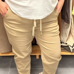 Jean beige clair en coton stretch, coupe droite ample, taille élastiquée avec cordon de serrage à nouer, poches latérales.
