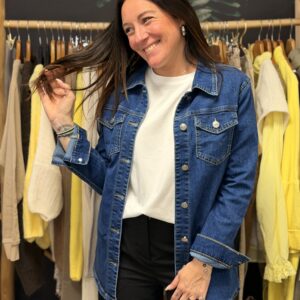 Femme aux cheveux longs bruns portant une chemise en jean bleu à boutons métalliques.