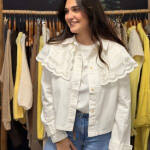 Femme aux cheveux longs bruns portant une veste cape blanche à col lavallière dentelle froncée, manches longues bouffantes.