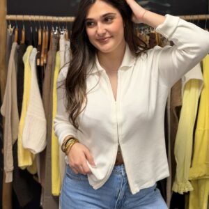 Jeune femme brune portant un gilet écru en maille douce, zippé sur le devant.