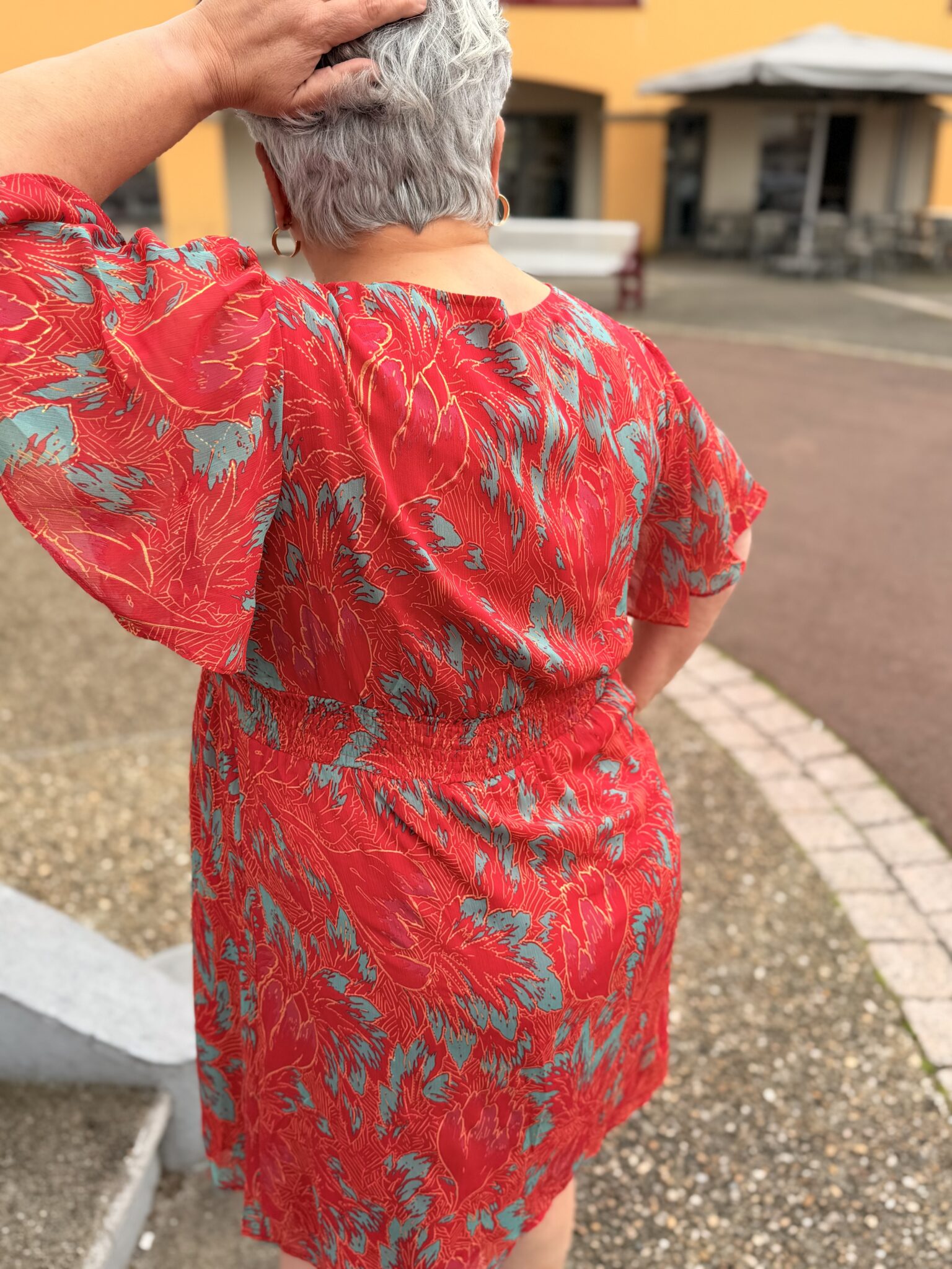 femme aux cheveux court porte robe courte rouge à motif floral