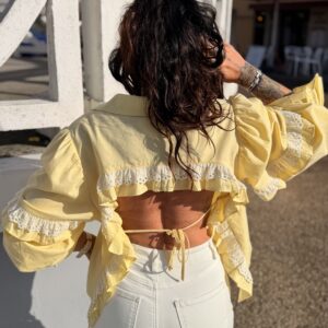 Femme aux cheveux brin mi long porte une chemise à volants et ouverte dans le dos avec un cordon très tendance et originale