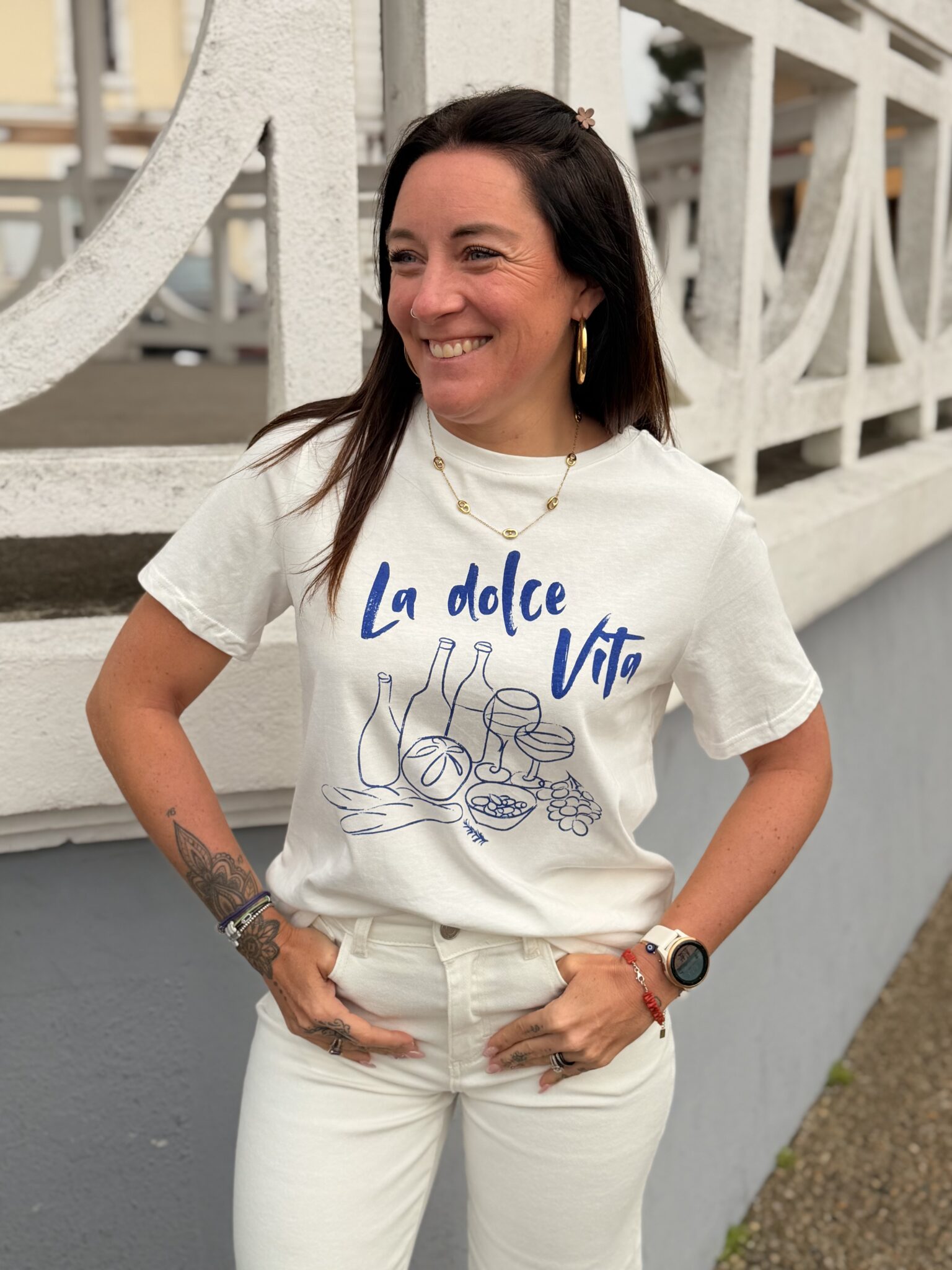 femme brune porte un tee-shirt blanc avec inscription dolce vita bleu électrique
