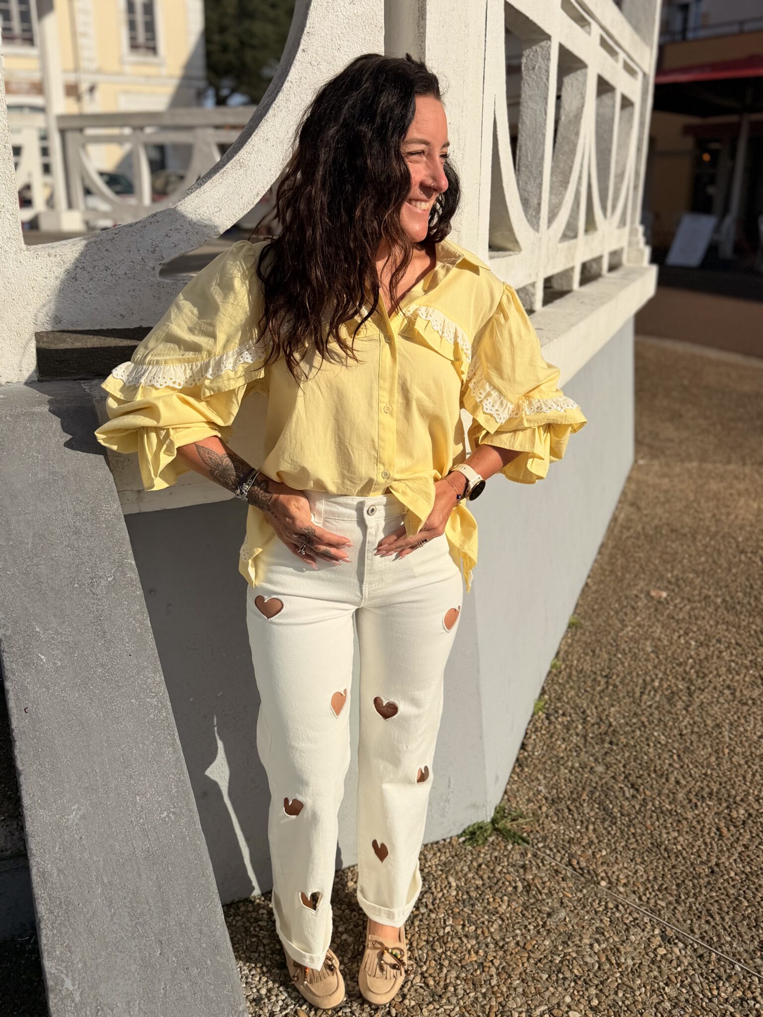 Femme aux cheveux brin mi long porte une chemise à volants et ouverte dans le dos avec un cordon très tendance et originale