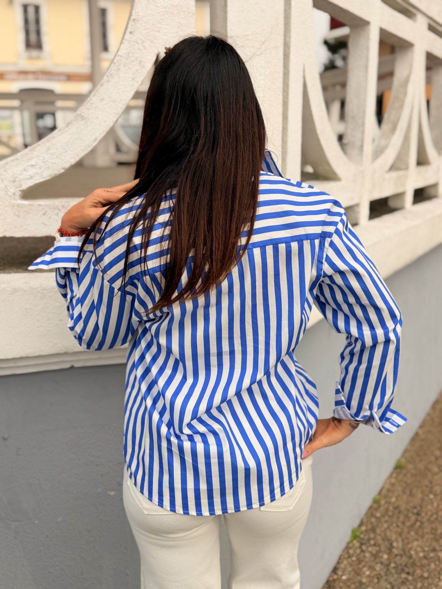 femme brune porte une chemise rayée bleu et blanche