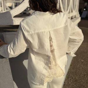 femme cheveux mi long portant une chemise blanche à dentelle ouverte dans le dos