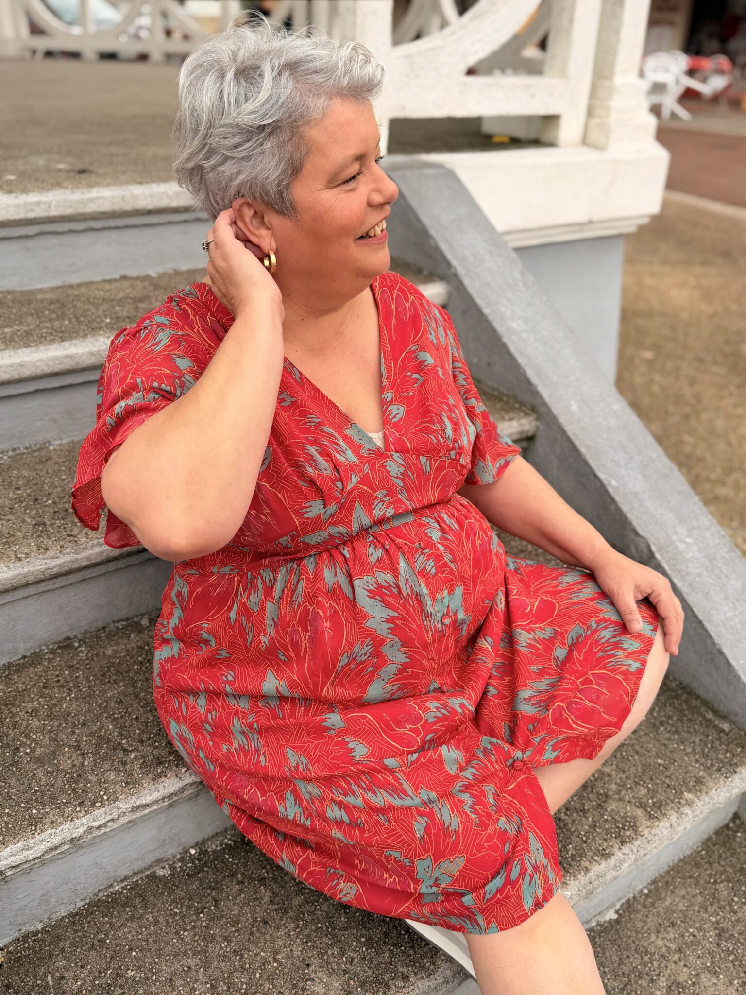 femme aux cheveux court porte robe courte rouge à motif floral