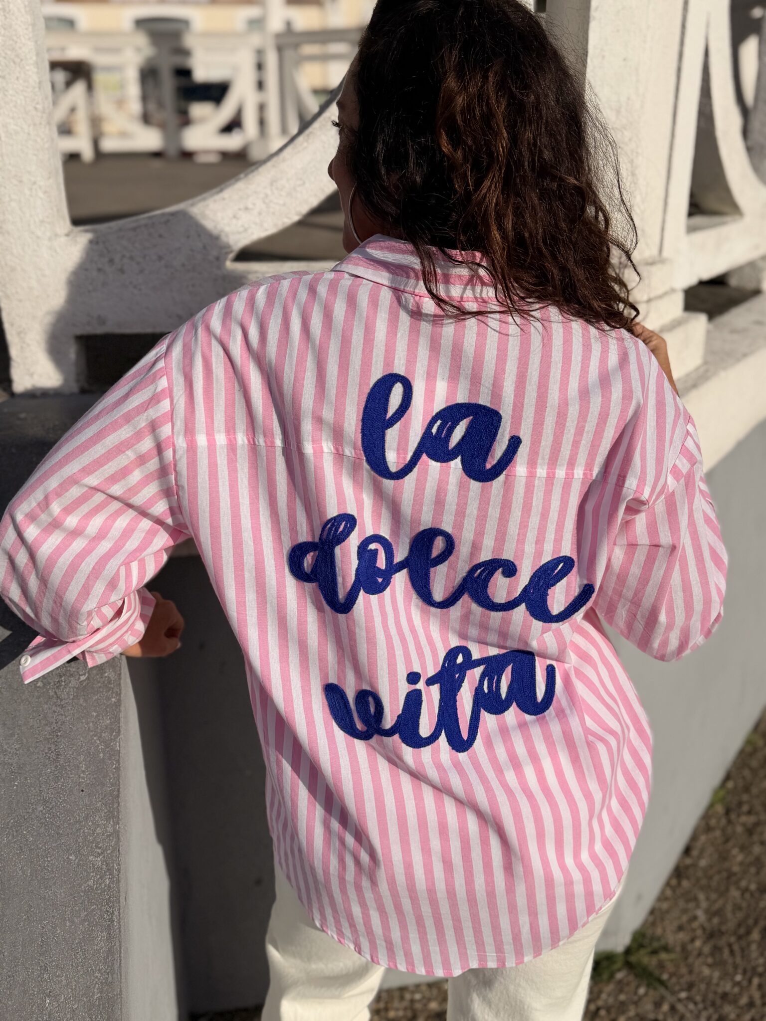 femme cheveux mi long brun porte une chemise à fines rayures avec une inscription dans le dos originale et tendance