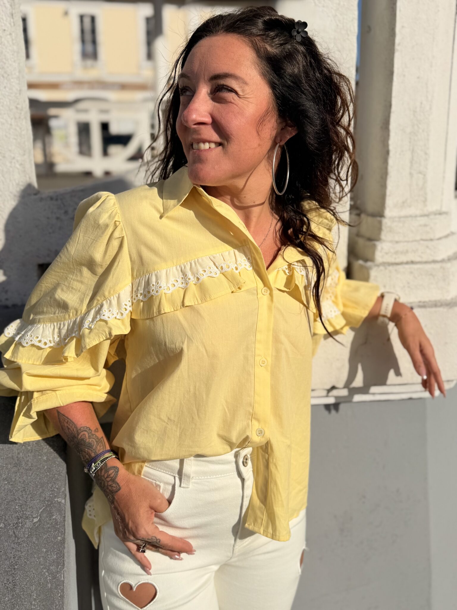 Femme aux cheveux brin mi long porte une chemise à volants et ouverte dans le dos avec un cordon très tendance et originale