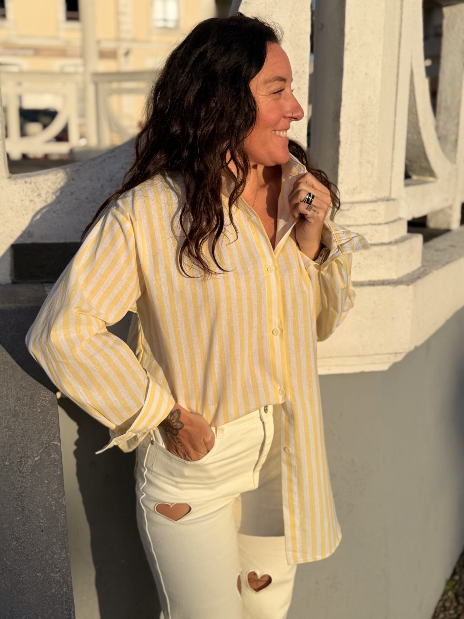 femme cheveux mi long brun porte une chemise à fines rayures avec une inscription dans le dos originale et tendance
