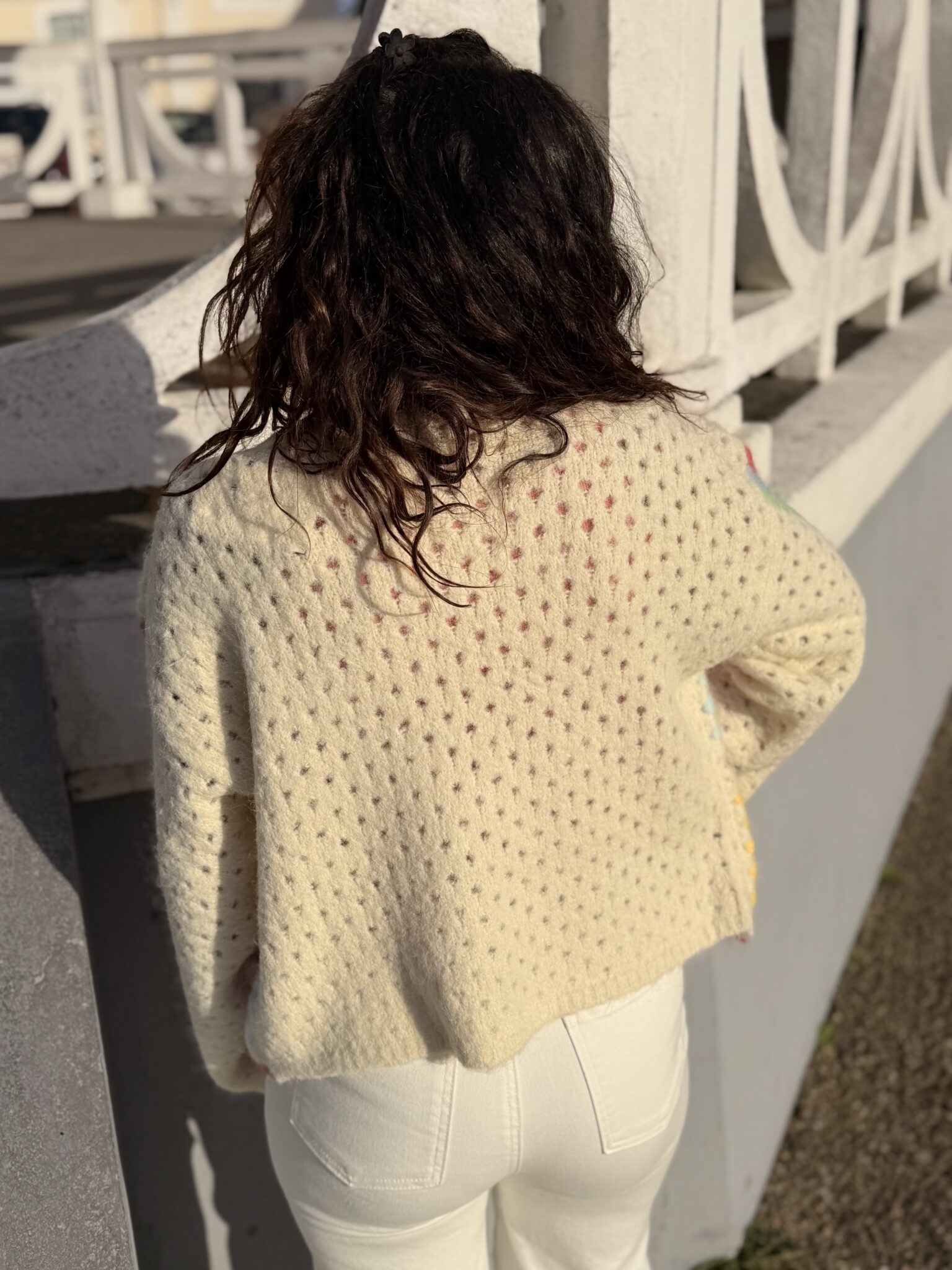 femme aux cheveux mi long brun porte un gilet en maille multicolore doux et tendance