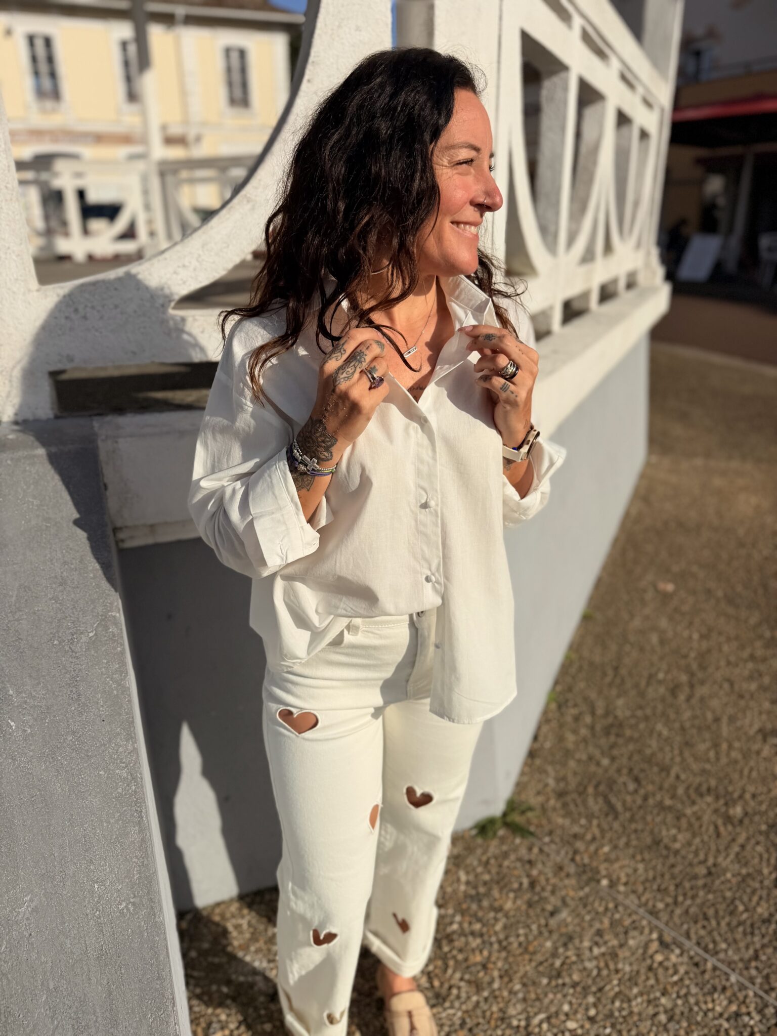 femme aux cheveux mi long brun portant une blouse blanche tendance et originale ouverte dans le dos avec des boutons