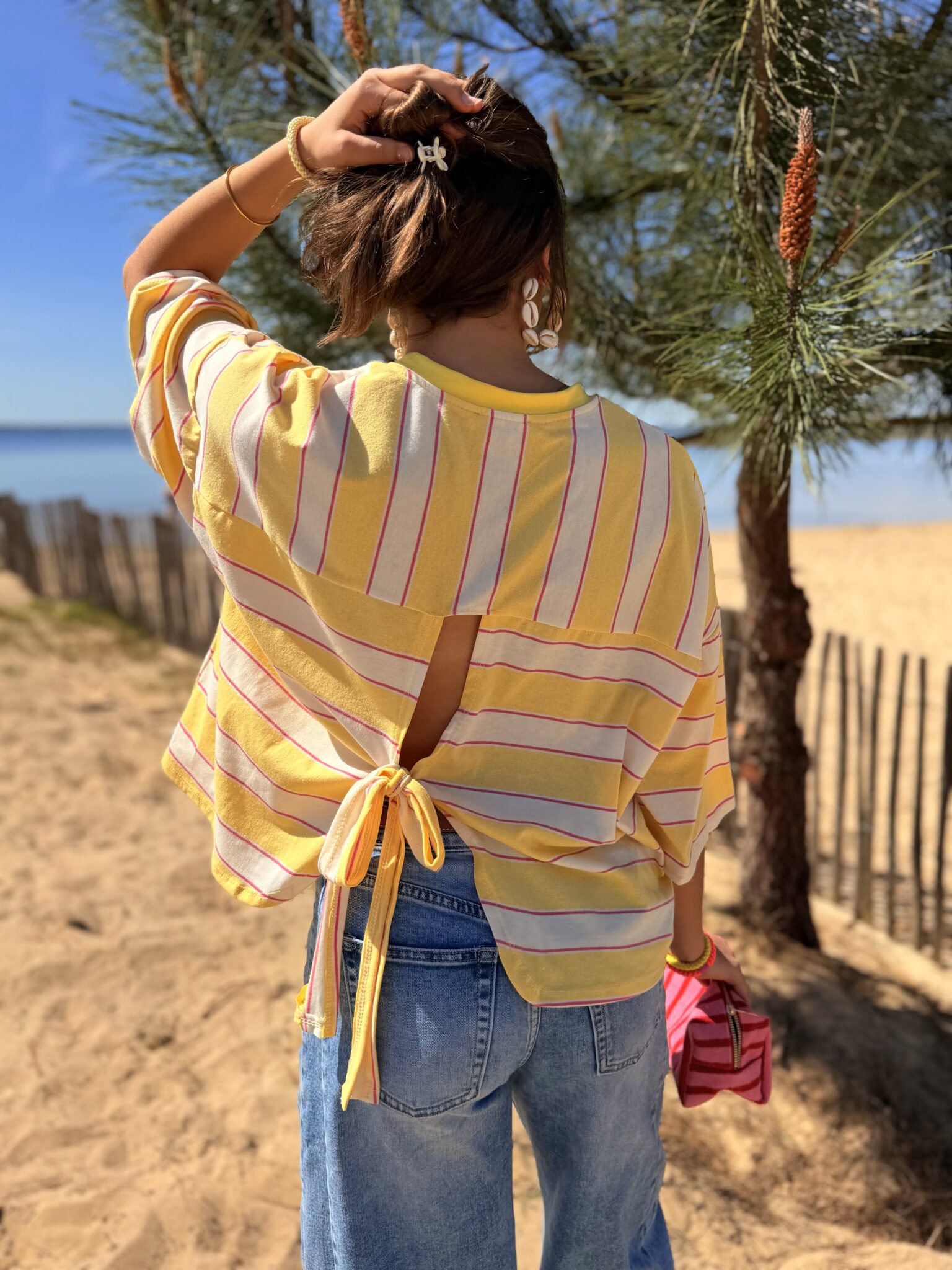 femme brune porte tee-shirt rayé jaune, rose, blanc