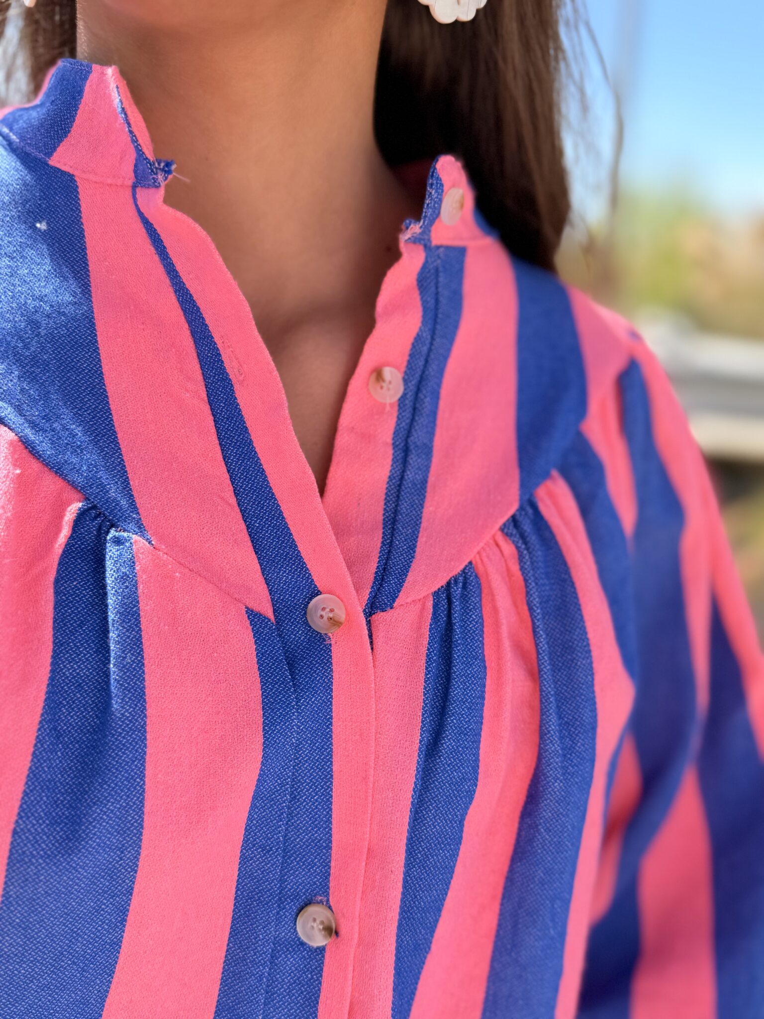 femme brune porte blouse rayé rose et bleu