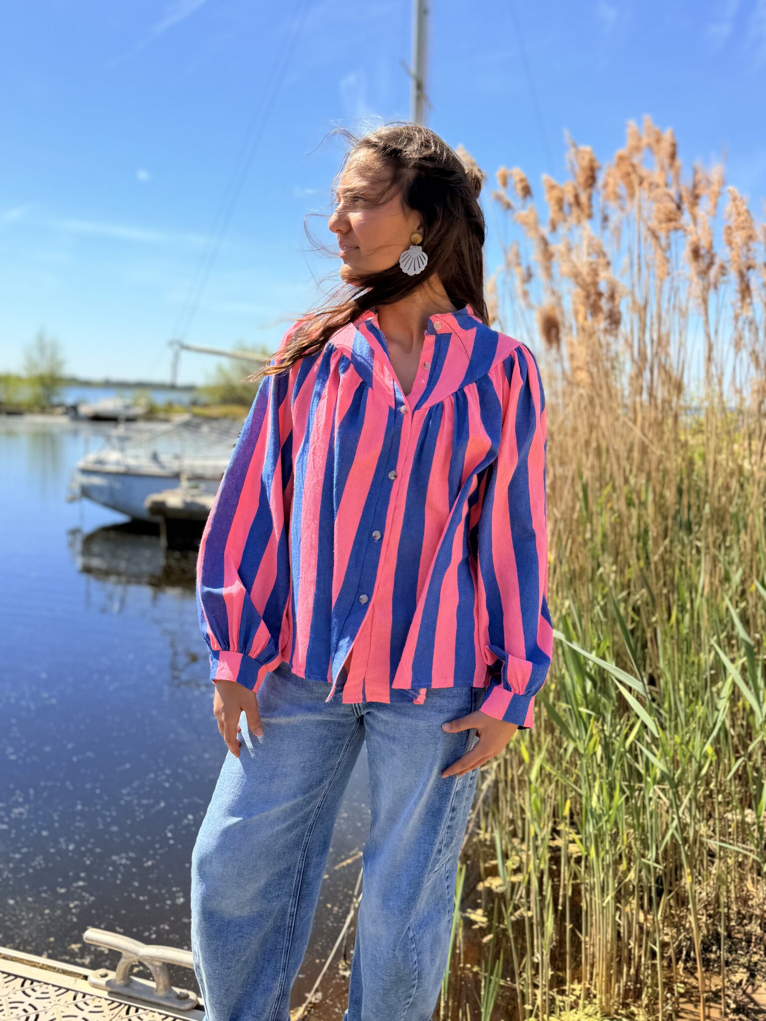 femme brune porte blouse rayé rose et bleu