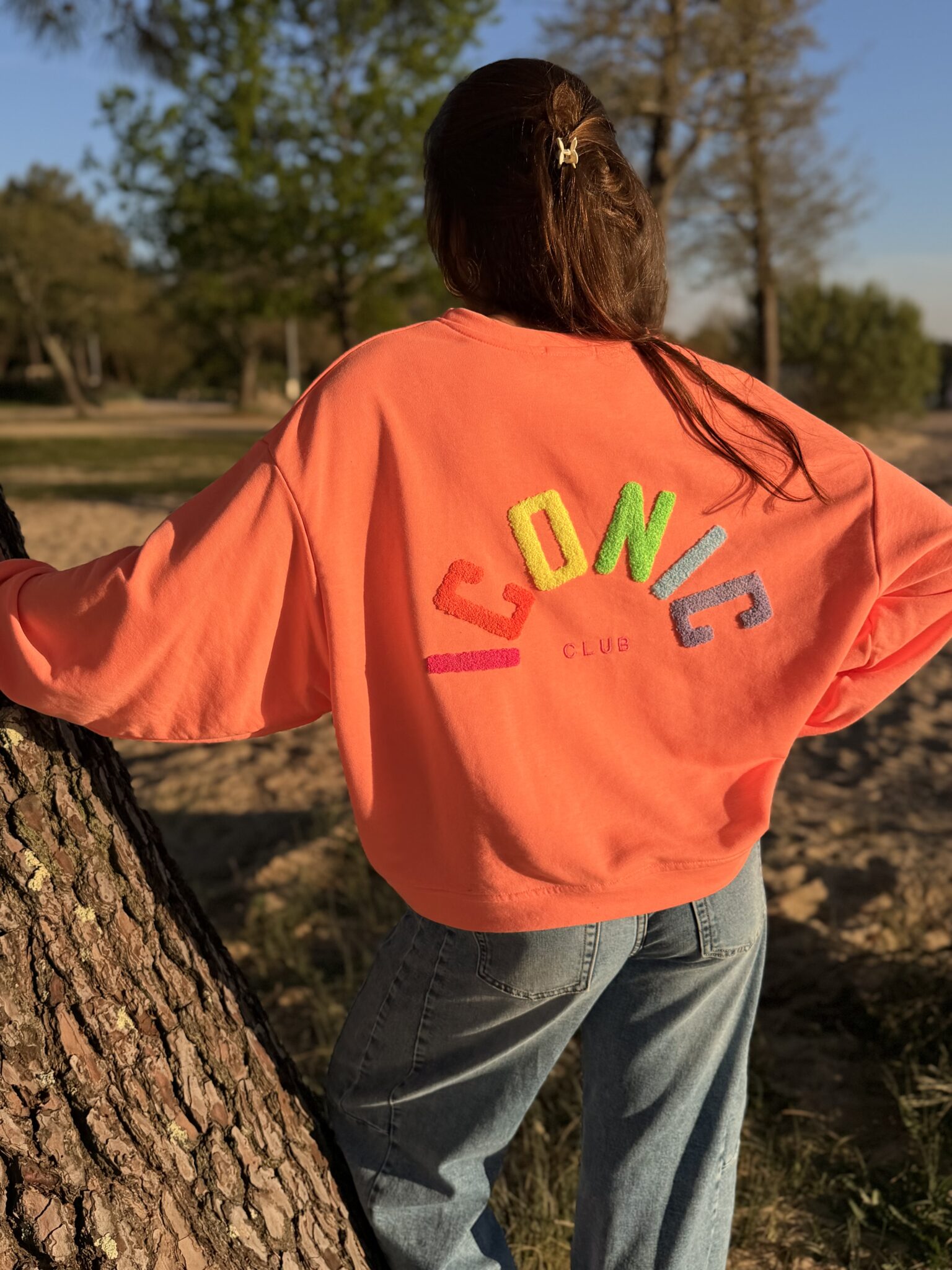 femme brune porte un sweat avec inscription iconic devant et derrière
