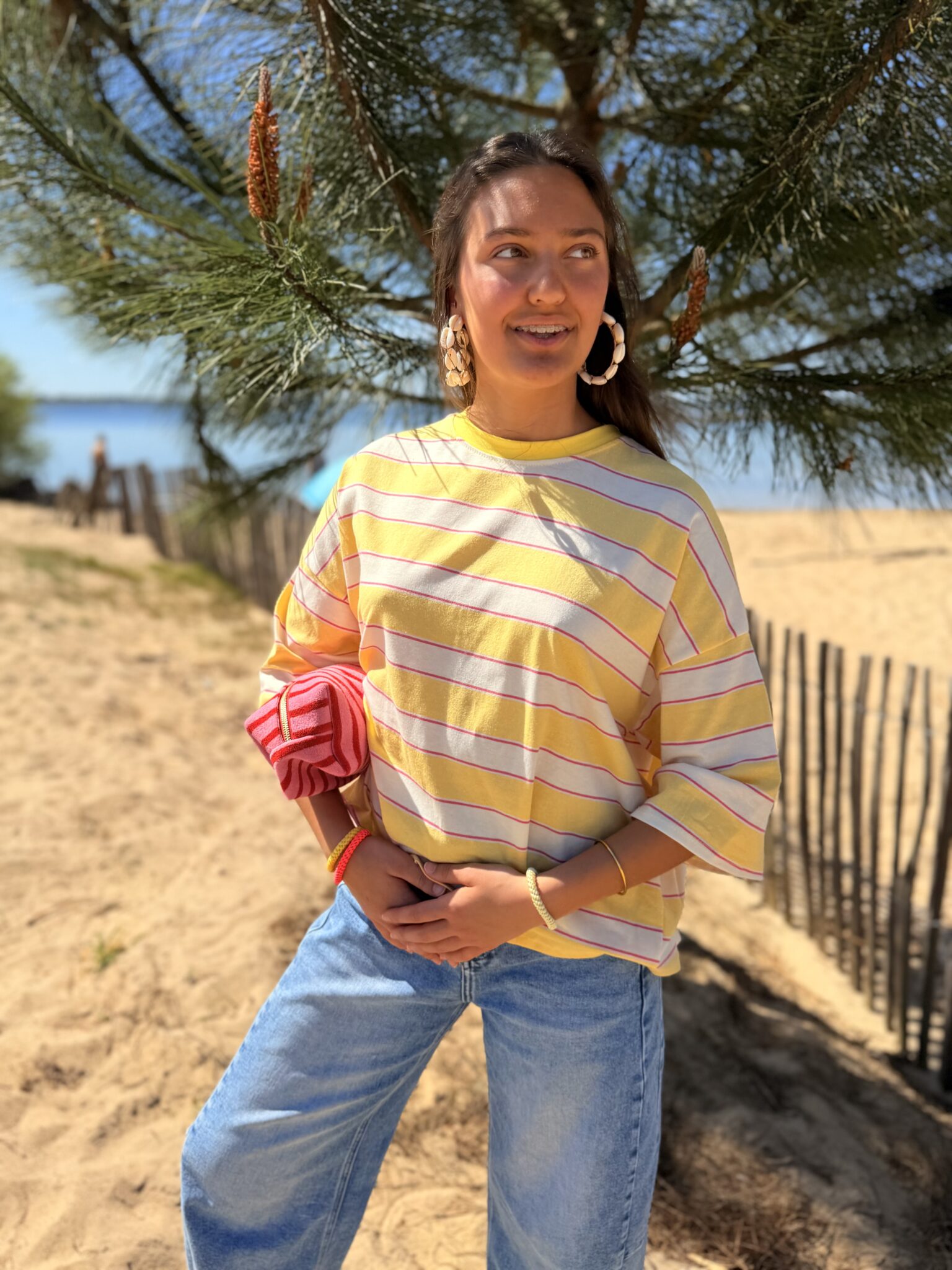 femme brune porte tee-shirt rayé jaune, rose, blanc