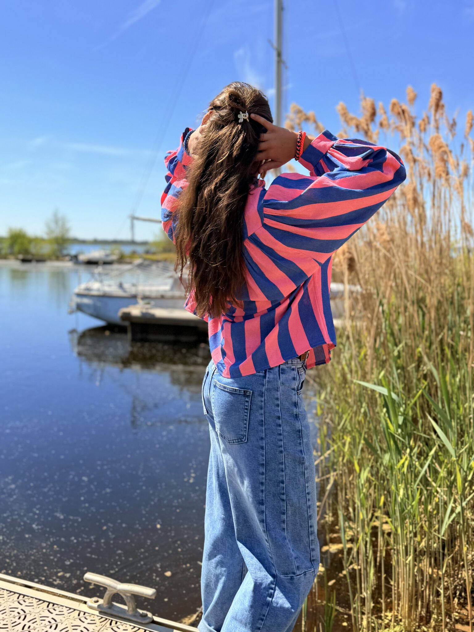femme brune porte blouse rayé rose et bleu