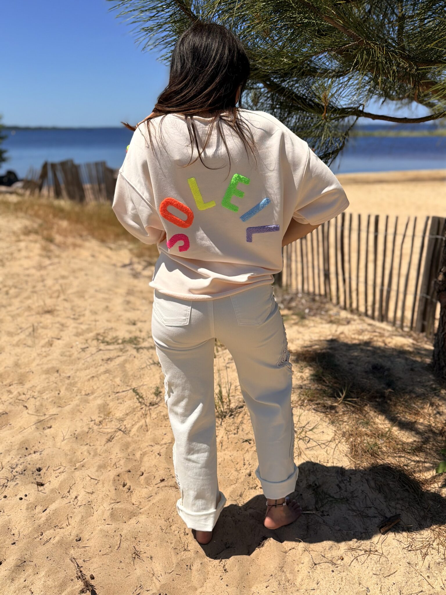 femme brune porte t-shirt oversize écriture dans le dos soleil couleur pêche