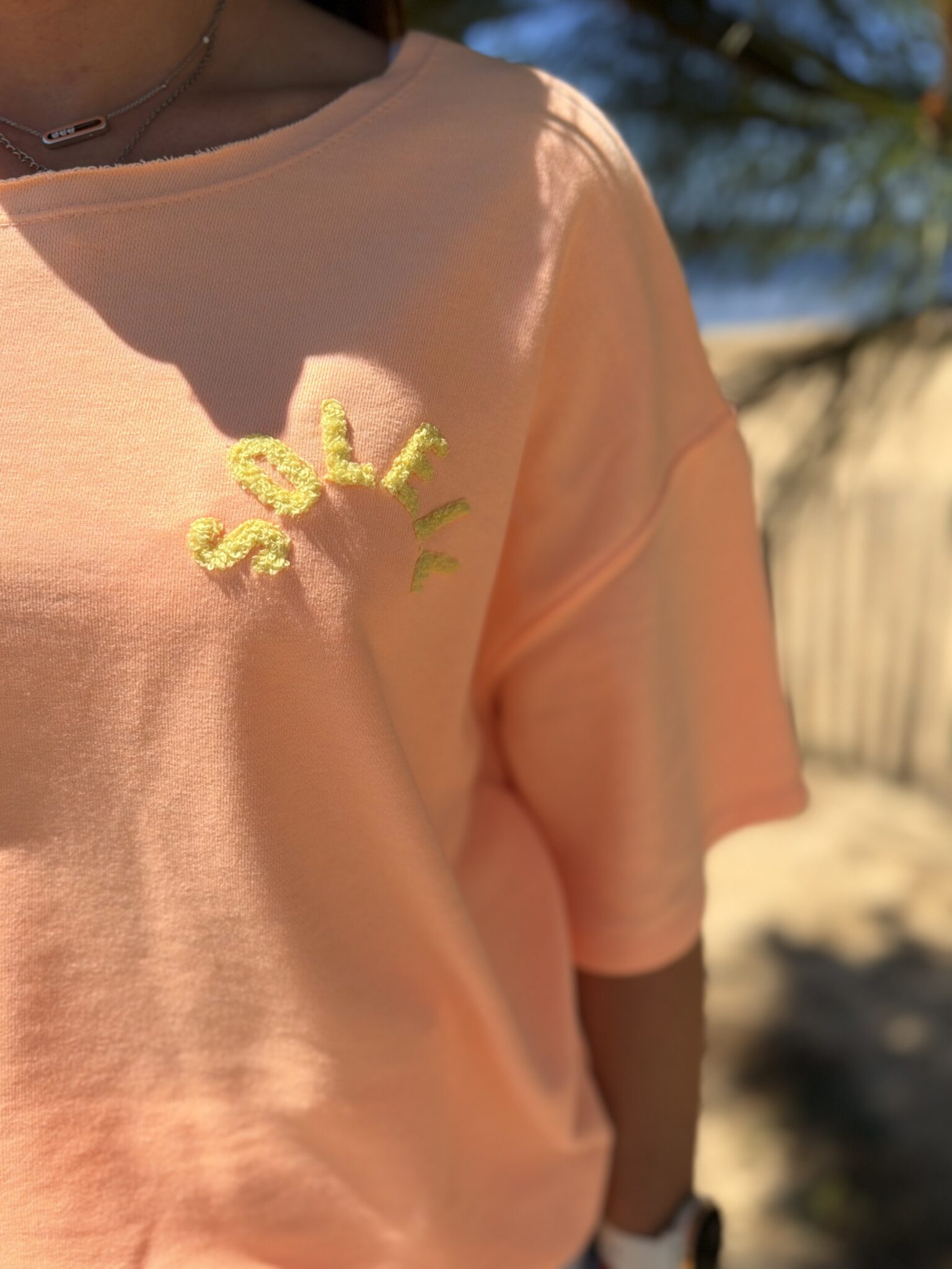 femme brune porte t-shirt oversize écriture dans le dos couleur corail orange