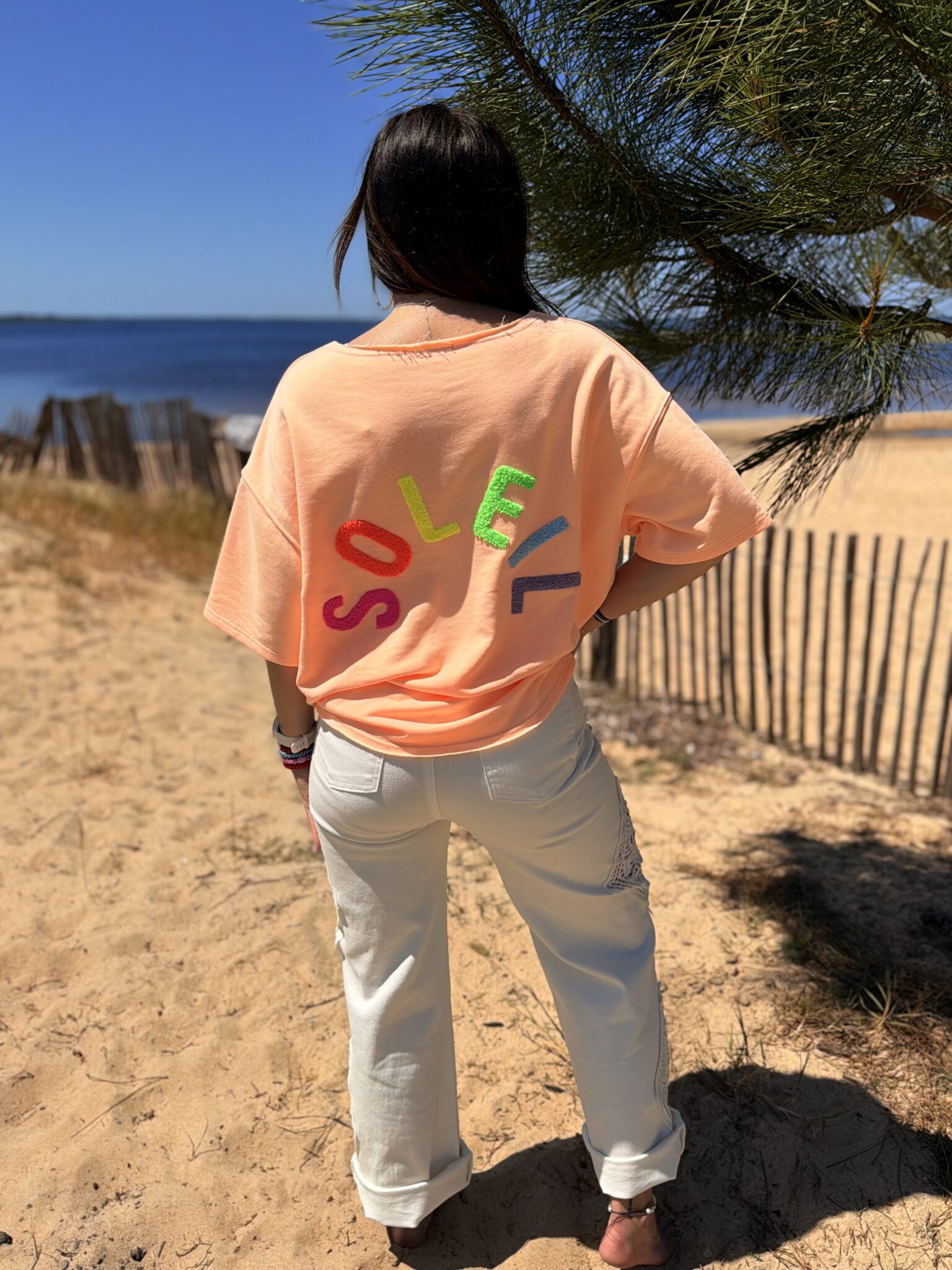 femme brune porte t-shirt oversize écriture dans le dos couleur corail orange