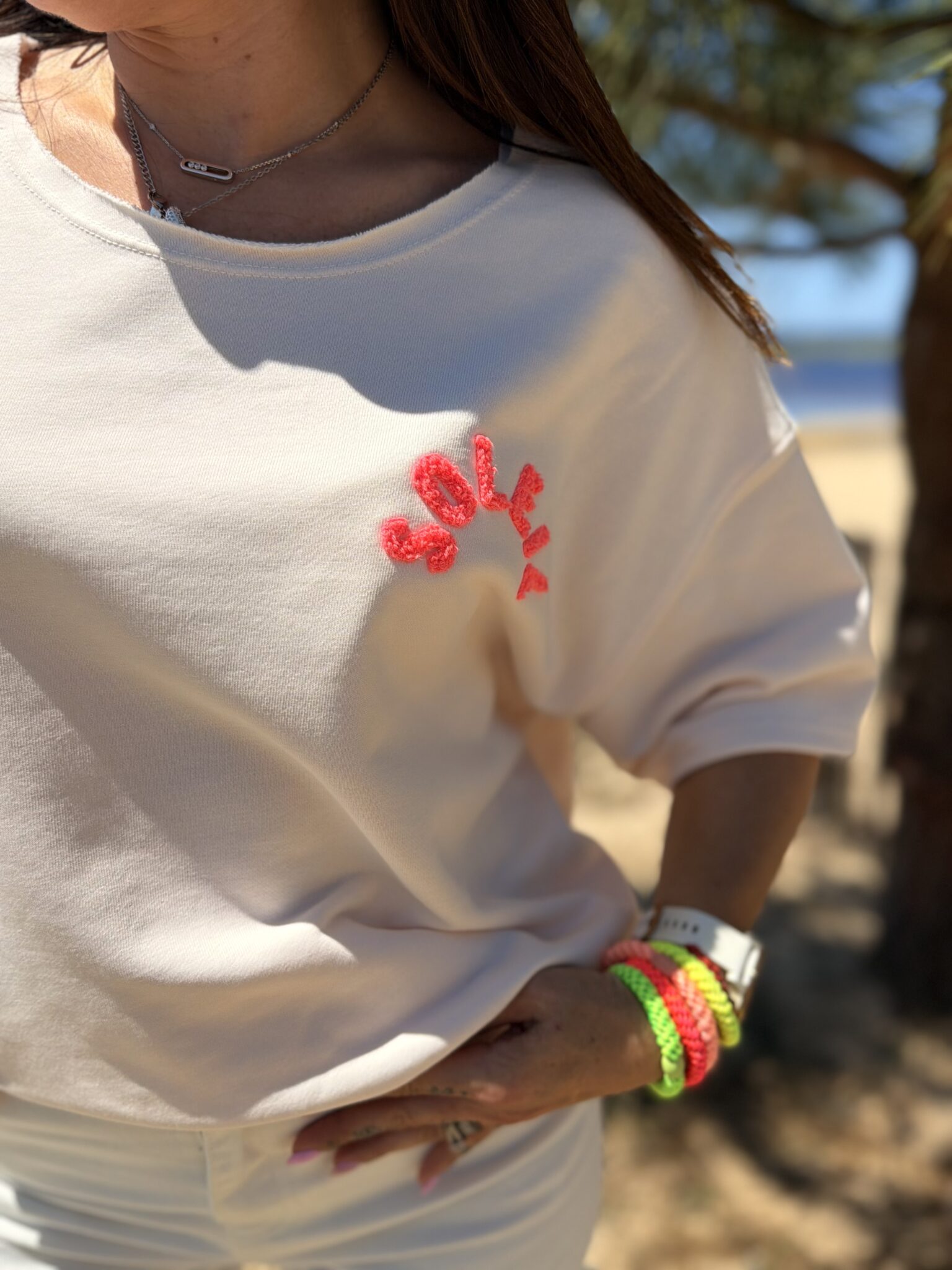 femme brune porte t-shirt oversize écriture dans le dos soleil couleur pêche
