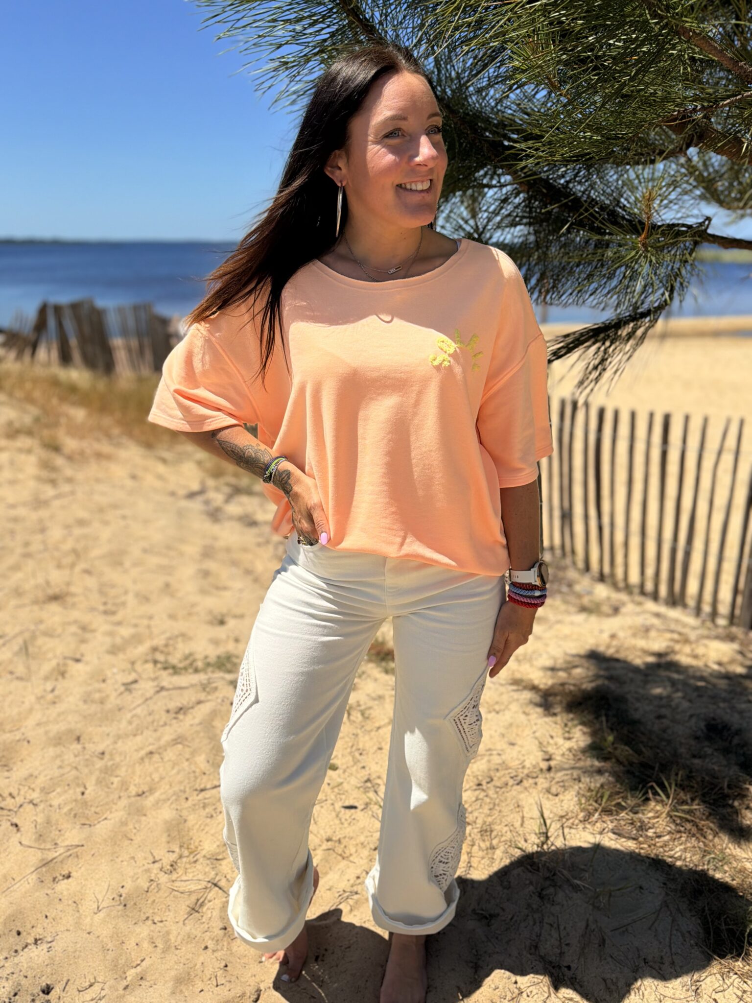 femme brune porte t-shirt oversize écriture dans le dos couleur corail orange