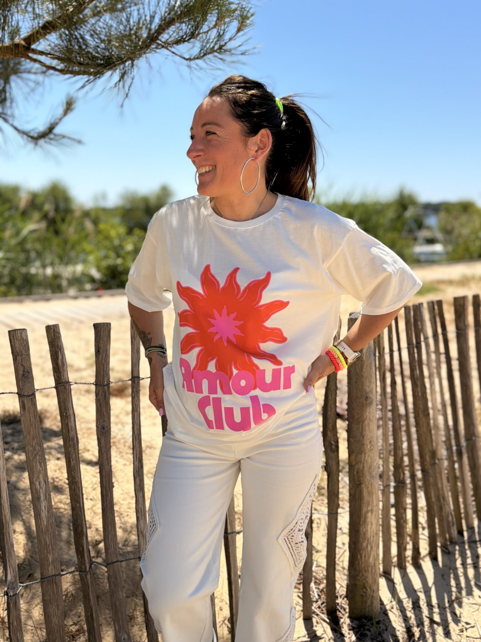femme brune porte t-shirt blanc oversize avec un fleur et écriture amour club
