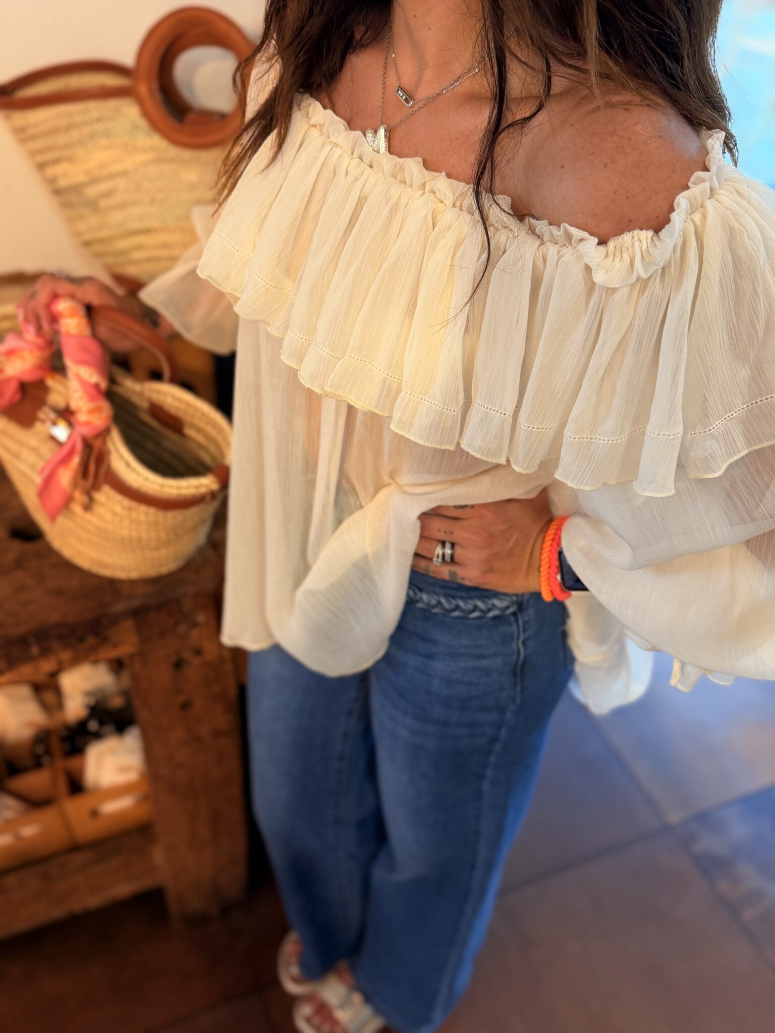 femme brune porte une blouse couleur crème style voilage épaules dénudées